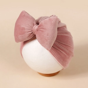 Détail d'un turban bébé en velours côtelé rose avec grand nœud et texture côtelée