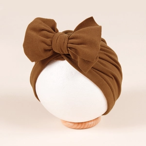 Detail of baby turban hat featuring a large bow and soft pleated caramel fabric