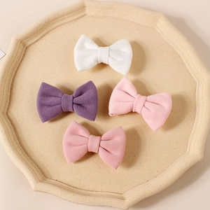 Macro shot of four colorful faux cashmere bow hair clips on a textured stone tray
