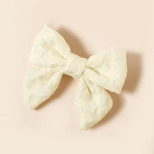 Vista dettagliata del fiocco per capelli in tessuto crema con motivo floreale jacquard
