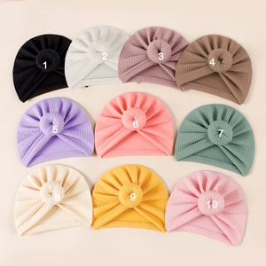 Flat lay of ribbed baby donut hats in 10 diverse colors with elastic waffle texture