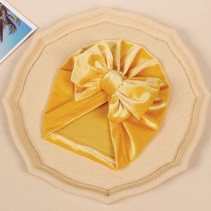 Detailed view of children's golden velvet hat featuring a large 3D bow decoration