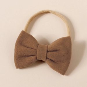 Close-up of a brown cashmere-like bow headwrap with a soft beige elastic nylon hairband