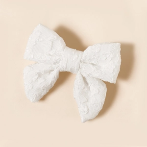 Dettaglio del fiocco per capelli in pizzo bianco con delicati ricami floreali fatti a mano