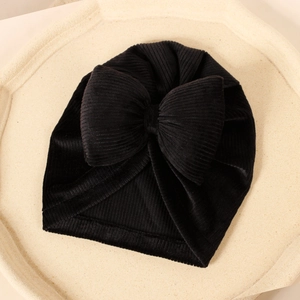 Détail du bonnet turban bébé en velours avec grand nœud et texture côtelée sur plat