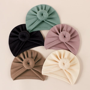 Flat lay of five ribbed knit baby turban hats with donut knots in various soft colors