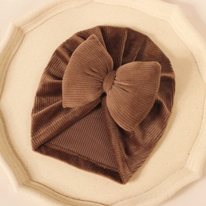 Détail d'un bonnet turban pour bébé en velours côtelé marron foncé avec grand nœud