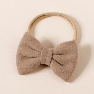 Detail view of a camel soft faux cashmere bow on a high-elastic nylon baby headband