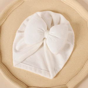 Gros plan sur le bonnet bébé blanc en tricot côtelé avec un grand nœud décoratif