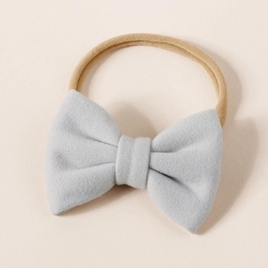 Close-up of a soft light blue cashmere-like bow on a stretchy nude nylon baby headband