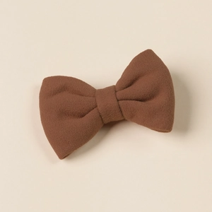 Close-up of brown faux cashmere bow hair clip with soft texture on beige background