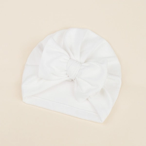 Detailed view of white baby turban hat with a large bow and soft knitted texture