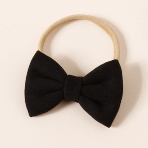 Detail view of black faux cashmere bow on a high-elastic nude nylon headband