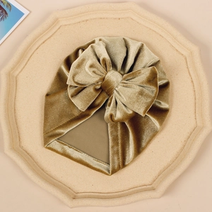 Detail of baby velvet turban hat in champagne gold with a large bow decoration