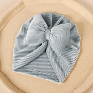 Détail du bonnet turban pour bébé avec un grand nœud et une texture en velours côtelé bleu