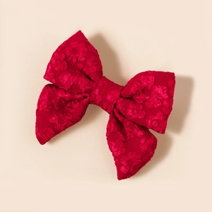 Dettaglio di un fermaglio a fiocco rosso scuro con trame floreali jacquard rifinite