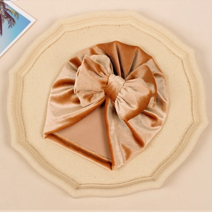 Detailed texture of baby velvet turban hat with oversized bow in caramel gold color