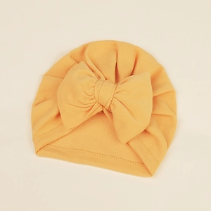Close-up of ginger yellow baby turban hat with a large decorative bow detail