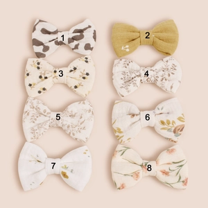 Détail de huit barrettes nœuds en coton aux motifs floraux et unis pour petites filles