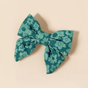 Dettaglio del fiocco in tessuto jacquard verde acqua per bambine con motivi floreali