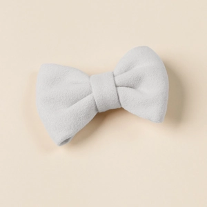Close-up of a soft grey imitation cashmere bow hair clip on a warm beige background