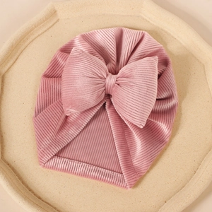 Détail du turban pour bébé avec texture en maille côtelée rose et grand nœud décoratif