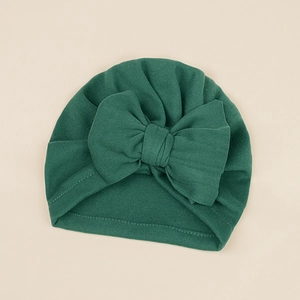 Close-up of a dark green baby turban hat with a large bow and soft knitted texture