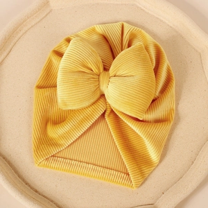 Gros plan d'un bonnet turban en velours côtelé jaune pour bébé avec grand nœud
