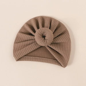 Detailed texture of ribbed knit baby turban with large donut knot in warm brown