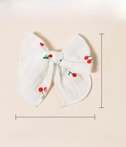 Detailed view of large cotton bow hair clip with red cherry floral print and soft fabric