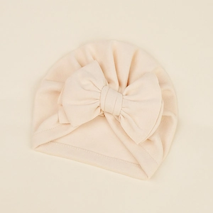Close-up of soft beige baby turban hat featuring a large decorative cashmere-like bow