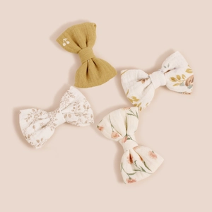 Détail de quatre barrettes à nœuds en coton avec motifs floraux et broderie cerise