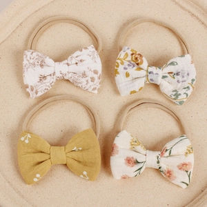 Detail von 4 Baby Nylon Stirnbändern mit floralen Baumwollschleifen in Erdtönen