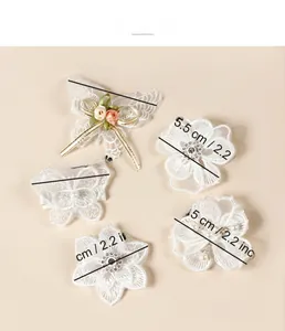 Vue détaillée des barrettes en dentelle blanche avec papillons, fleurs et perles fantaisie