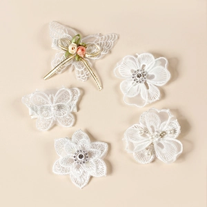 Détail de pinces à cheveux en dentelle blanche avec papillon 3D, fleurs et perles