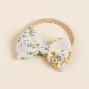 Detailansicht der geblümten Baumwollschleife auf einem weichen Babystirnband aus Nylon