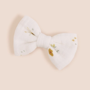 Détail d'un nœud papillon en coton blanc à motif floral jaune pour filles sur fond doux