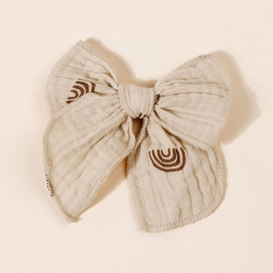Close-up of muslin fabric bow hair clip with minimalist brown rainbow pattern print