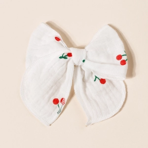 Detail of double-layer gauze bow hair clip featuring a red cherry print pattern