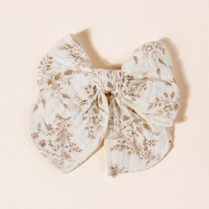 Close-up of floral bow hair clip made of white cotton linen with brown flower patterns