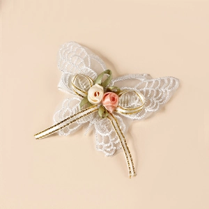 Détail d'une pince à cheveux papillon en dentelle brodée avec roses en satin et rubans