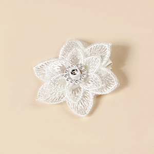 Gros plan sur pince à cheveux fleur en dentelle blanche avec centre en diamant brillant