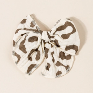Detail of floral cow pattern bow hair clip with rustic frayed edges on cotton fabric