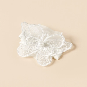 Détail d'une pince à cheveux papillon en dentelle blanche brodée avec perle centrale au milieu