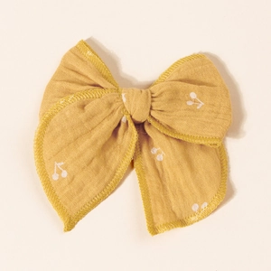 Detailed texture of yellow cotton hair clip with delicate white cherry floral patterns