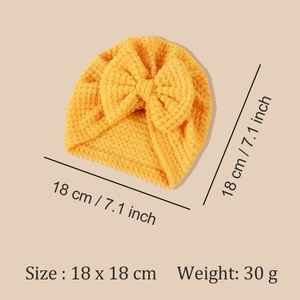 Détail du bonnet tricoté jaune pour bébé avec grand nœud et dimensions de 18x18cm