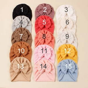Vue à plat de 15 turbans tricotés colorés pour bébés sur un fond beige doux