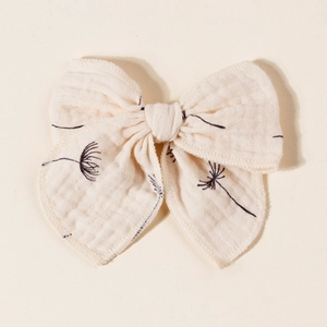 Detailed close-up of muslin fabric bow hair clip with black dandelion floral print