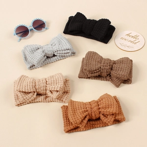 Detail view of five Morandi colored knitted waffle bow headbands for infants and babies