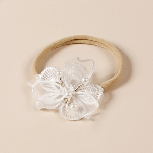 Détail du bandeau bébé en nylon avec fleur en dentelle blanche et perles fines